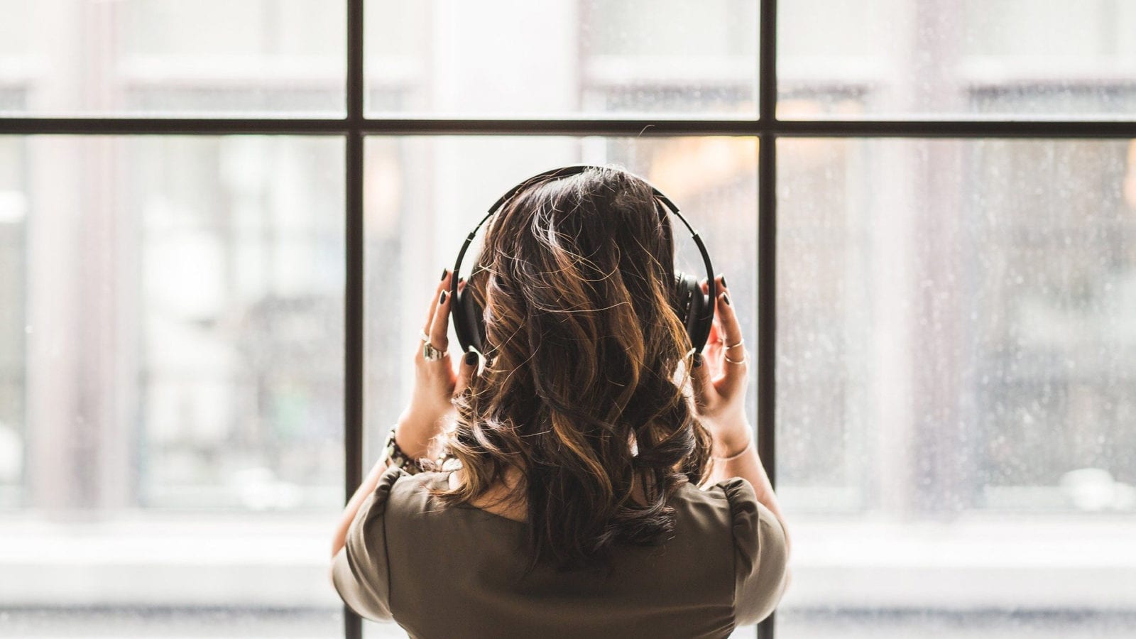 woman with headphones on listening to the Leading Learning Podcast