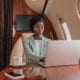 Woman of color using laptop on airplane for elearning translation-localization concept