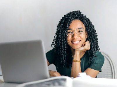 smiling woman participating in an online course on her laptop